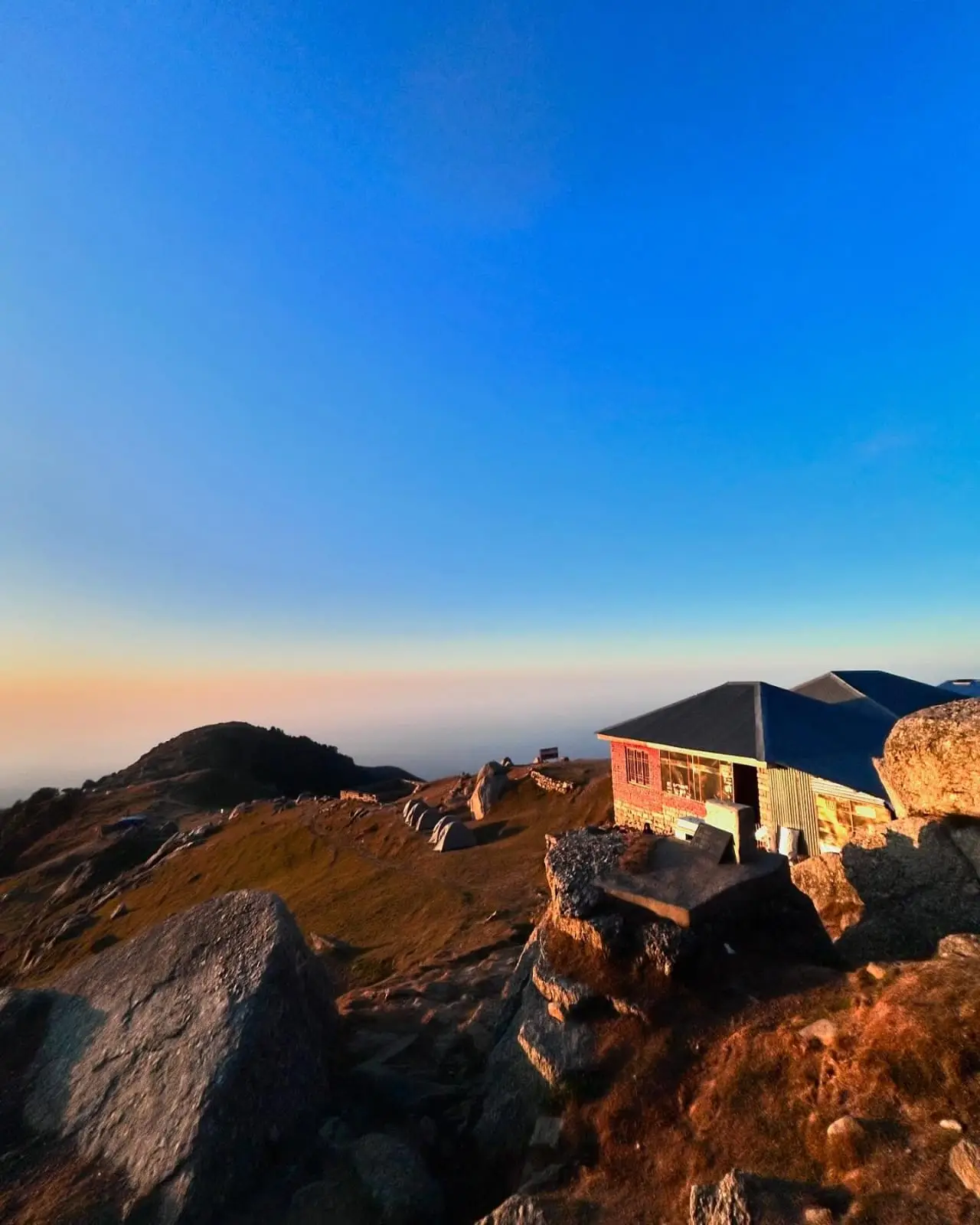 Sunrise over a rocky mountaintop with a small hut