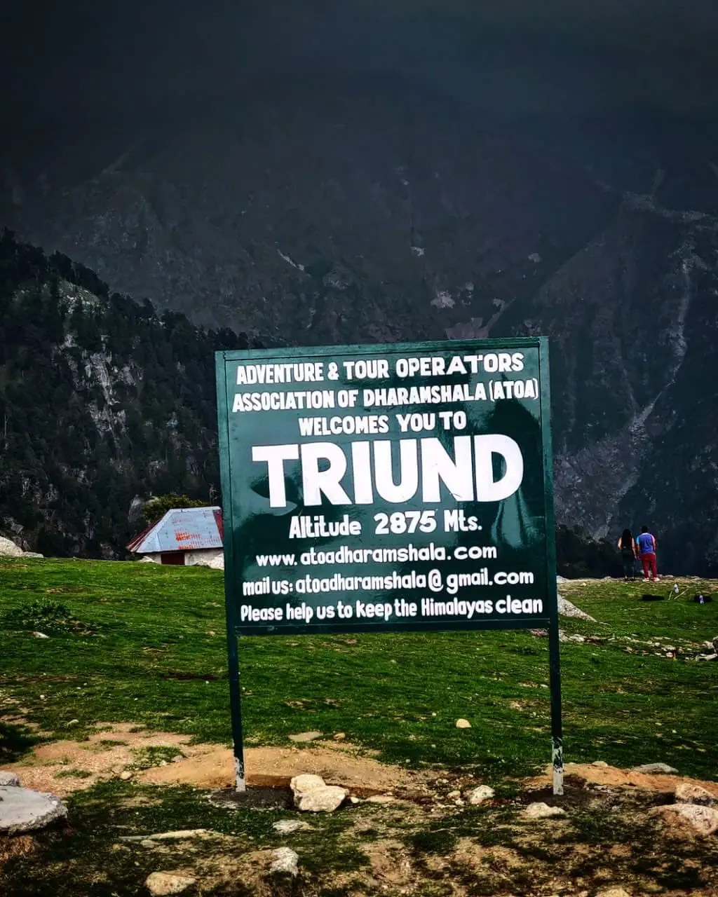 A traveller beside the Triund welcome sign at 2,875 metres, Dharamshala